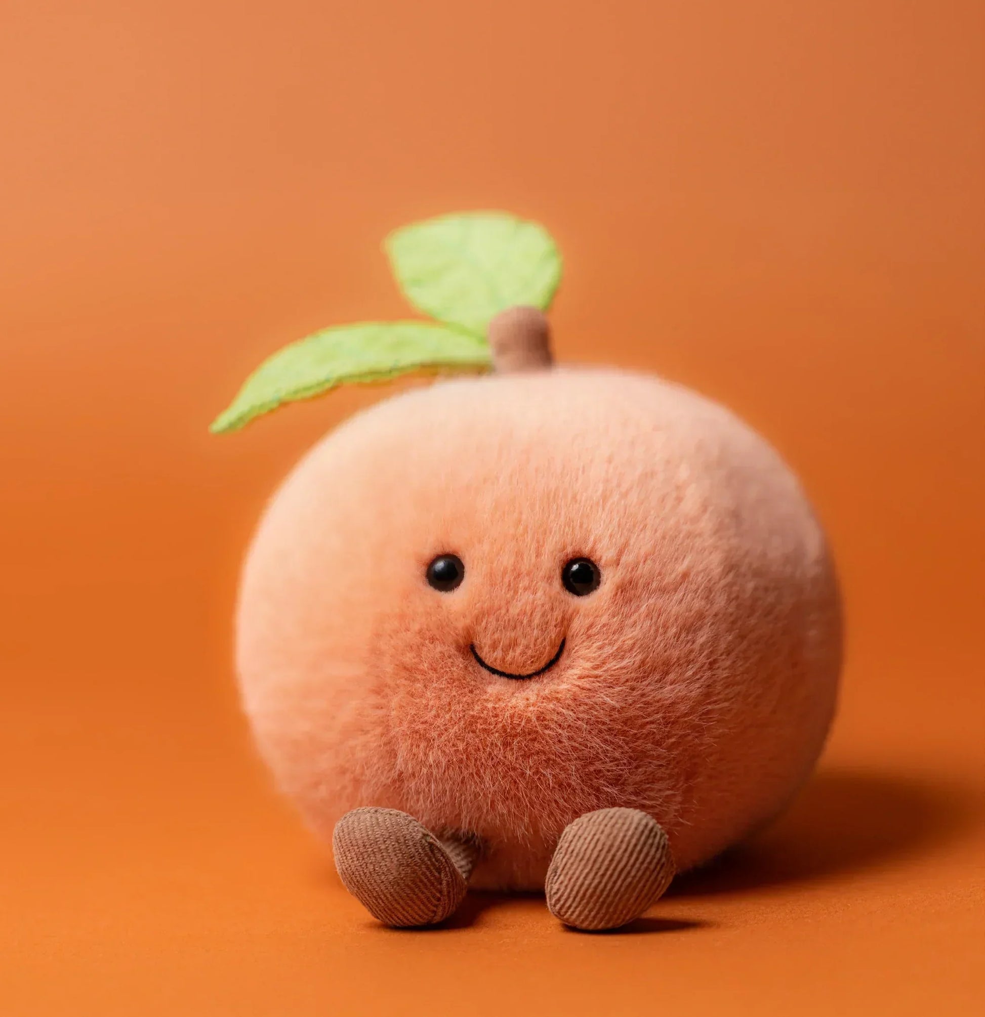 Jellycat Amuseables Peach plush toy with soft, fuzzy texture and cheerful facial expression, perfect for cuddling and play.
